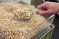 Mens hand scoops up salted roasted peanuts with a spatula in a store. Royalty Free Stock Photo