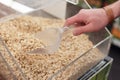 Mens hand scoops up salted roasted peanuts with a spatula in a store. Royalty Free Stock Photo