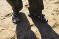 Mens legs in long trousers and Slippers on the sandy beach Royalty Free Stock Photo