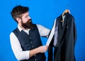 At mens shop. Shop assistant offering wide choice of business casual wear. Bearded man matching luxury necktie to coat
