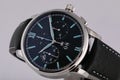 Mens silver watch with a black dial, blue clockwise, chronograph, stopwatch, with a black leather strap with blue line. Royalty Free Stock Photo