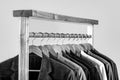 Mens suits in different colors hanging on hanger in a retail clothes store, close-up. Mens shirts, suit hanging on rack