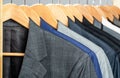 Mens suits in different colors hanging on hanger in a retail clothes store, close-up. Mens shirts, suit hanging on rack Royalty Free Stock Photo