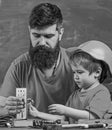 Mens work concept. Boy, child busy in protective helmet makes by hand, repairing, does crafts with dad. Father with