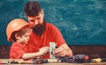 Mens work concept. Boy, child in protective helmet makes by hand, repairing, does crafts with dad. Father with beard and