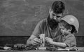 Mens work concept. Boy, child in protective helmet makes by hand, repairing, does crafts with dad. Father with beard and