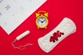 Menstrual calendar with feminine products and yellow alarm clock on red background