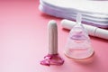 Menstrual cup and feminine hygiene tampon, isolated on pink background. Feminine hygiene products. Copy space