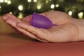 Menstrual Cup on red or black background in the girl hand, low key. woman hands folding a menstrual cup. lights in the background. Royalty Free Stock Photo