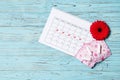 Menstrual cycle calendar on a blue wooden background. Gerbera and tampons, pads. Ovulation concept. Royalty Free Stock Photo