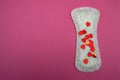 Menstrual pad with a red glitter on pink background the slim cotton