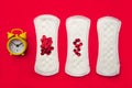 Menstrual pads with bright red glitter and alarm on red background. Woman periods cycle, menstruation frequency