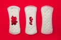Menstrual pads with bright red glitter on red background. Woman periods cycle, menstruation frequency. Minimalist still