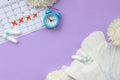 Menstrual pads and tampons on menstruation period calendar with blue alarm clock and white flowers Royalty Free Stock Photo