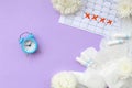 Menstrual pads and tampons on menstruation period calendar with blue alarm clock and white flowers Royalty Free Stock Photo