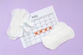 Menstrual pads and tampons on menstruation period calendar flat lay on lilac background Royalty Free Stock Photo