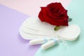 Menstrual pads and tampons with red rose flower on multicolored background