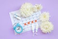 Menstrual tampons on menstruation period calendar with blue alarm clock and white flowers