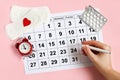 Menstruation calendar with pads, alarm clock, hormonal contraceptive pills. Female's menstrual cycle concept. Menstrual