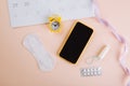 Menstruation calendar and smartphone with cotton tampon, sanitary pad and yellow alarm clock on pink background. Woman Royalty Free Stock Photo