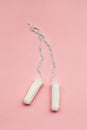 Menstruation cycle, feminine hygiene and protection, pair of cotton tampons on pastel pink background, top view