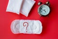 Menstruation , period delay concept with Sanitary napkin with question mark on pad and alarm clock on red background