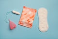 Menstruation products, intimate hygiene and protection, sanitary pads, tampon and menstruation cup on blue