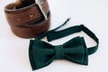 Menswear set. Men`s accessories. Green bow tie and leather belt on a white background. Wedding morning Royalty Free Stock Photo