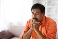 Closeup of sad mature indian man sitting on couch alone Royalty Free Stock Photo