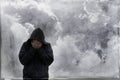 A mental health, emotional concept. Of a hooded man holding his head in his hands, with storm clouds behind. With a painted grunge Royalty Free Stock Photo