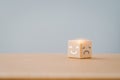 mental health and emotional state concept, white smiling face in bright side and unhappy grey face in dark side on wooden cube Royalty Free Stock Photo