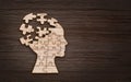 Mental health symbol. Human head silhouette with a puzzle cut out from wooden background