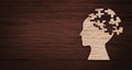 Mental health symbol. Human head silhouette with a puzzle cut out from wooden background Royalty Free Stock Photo