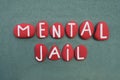 Mental Jail, negative mental state text composed with red colored stone letters over green sand