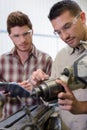 mentor and young apprentice adjusting piece metal Royalty Free Stock Photo