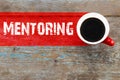 Mentoring / Cup of coffee with mentoring inscription on wooden b Royalty Free Stock Photo