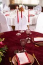 The menu card lies on a red napkin on plates, a gilt fork and knife on the sides of the plate, a glass of brown glass, flower Royalty Free Stock Photo