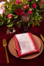 The menu card lies on a red napkin on plates, a gilt fork and knife on the sides of the plate, a glass of brown glass, flower Royalty Free Stock Photo