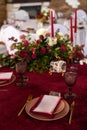 The menu card lies on a red napkin on plates, a gilt fork and knife on the sides of the plate, a glass of brown glass, flower Royalty Free Stock Photo