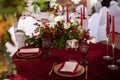 The menu card lies on a red napkin on plates, a gilt fork and knife on the sides of the plate, a glass of brown glass, flower Royalty Free Stock Photo