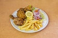 Menu plate with pieces of broaster chicken in batter with salad guarnicion with purple onion with lemon