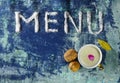 Menu text made of salt with cup of milk, walnuts, bay leaves and petals  on blue rugged background Royalty Free Stock Photo