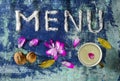 Menu text made of salt with cup of milk, walnuts, bay leaves and petals  on blue rugged background Royalty Free Stock Photo