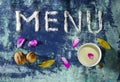 Menu text made of salt with cup of milk, walnuts, bay leaves and petals  on blue rugged background Royalty Free Stock Photo