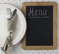 Menu title written white chalk on blackboard with table setting knife and fork lying on tablecloth polka dot. Copy space for your