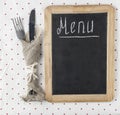 Menu title written white chalk on blackboard with table setting knife and fork lying on tablecloth polka dot. Copy space for your