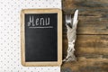Menu title written white chalk on blackboard with table setting knife and fork lying on tablecloth polka dot. Copy space for your