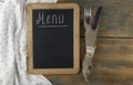 Menu title written white chalk on blackboard with table setting knife and fork lying on tablecloth polka dot. Copy space for your