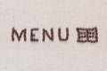 Menu word with icon made from roasted coffee beans on linen creamy linen canvas, shot from above, close up