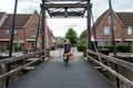 Meppel, Overijssel, The Netherlands, Post office delivery man driving his bike over an old bridge Royalty Free Stock Photo